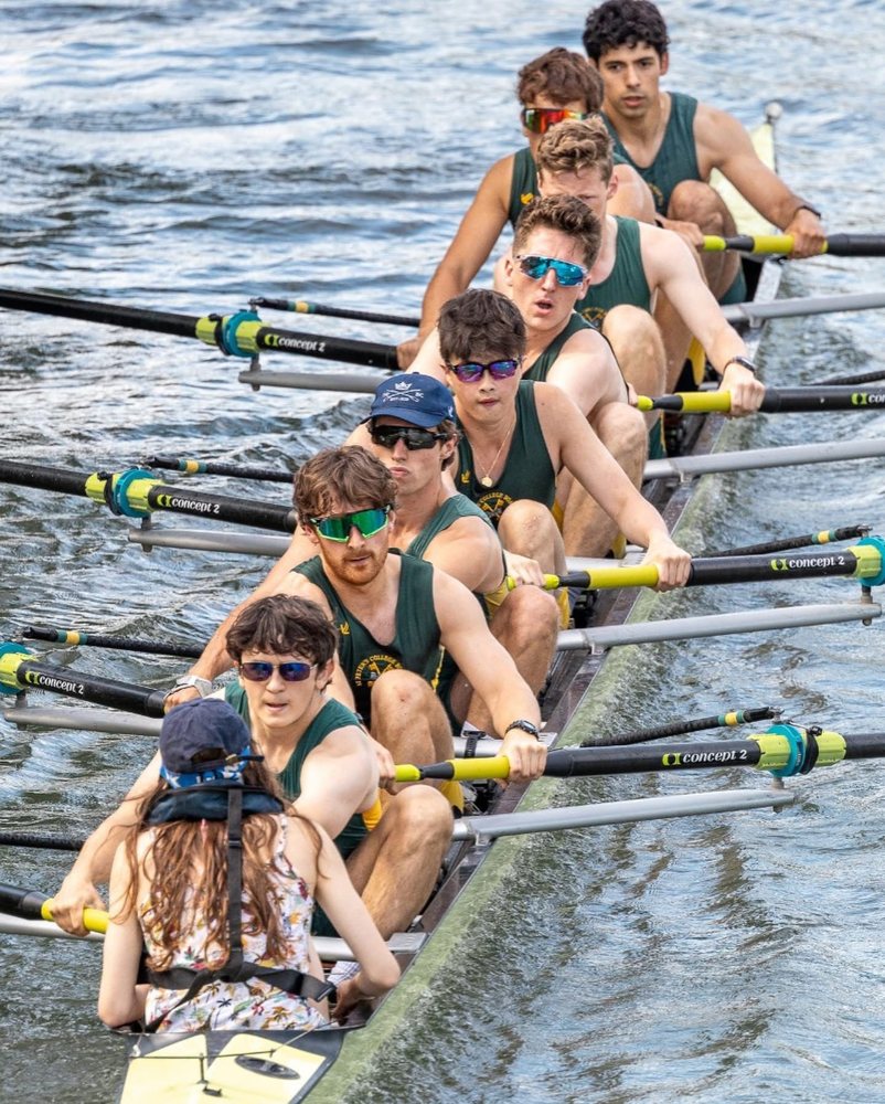 A men's eight in sunglasses mid-stroke